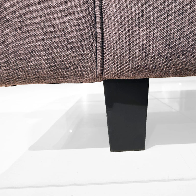 Close-up of a brown upholstered chair with a black metal leg
