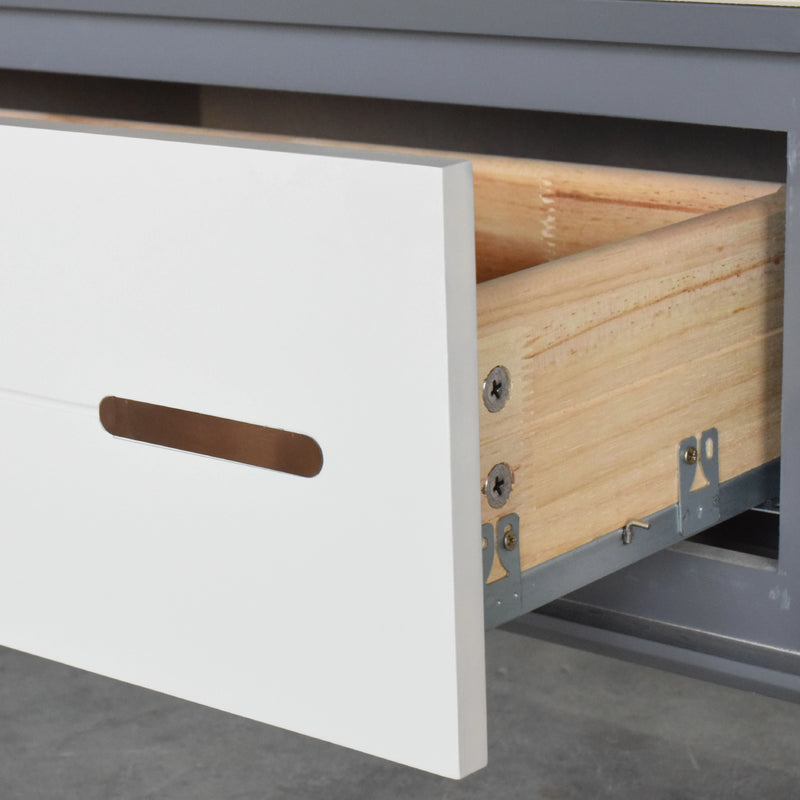 Close-up of a white drawer with a wooden interior and metal handle on a gray surface.