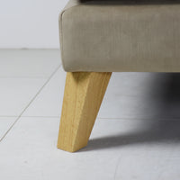 Close-up of a beige upholstered chair with wooden legs on a light gray floor.
