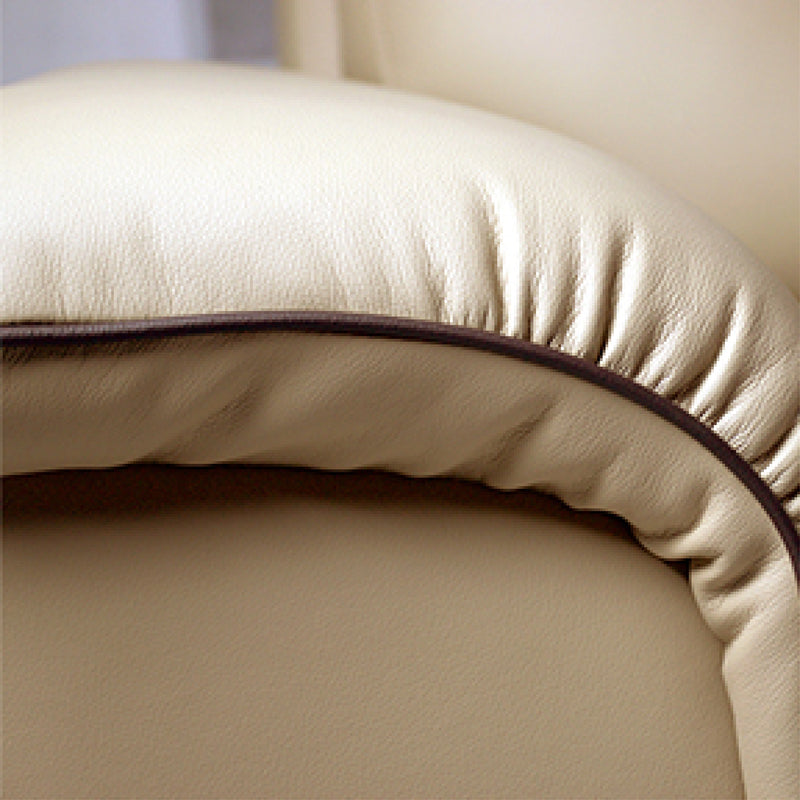 Close-up of a beige leather armchair with a brown trim.