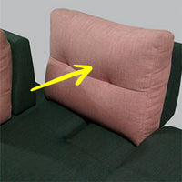 Pink cushion on a green sofa with a yellow arrow pointing to it.