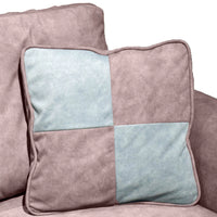 Patchwork pillow with pink and light blue squares on a sofa.