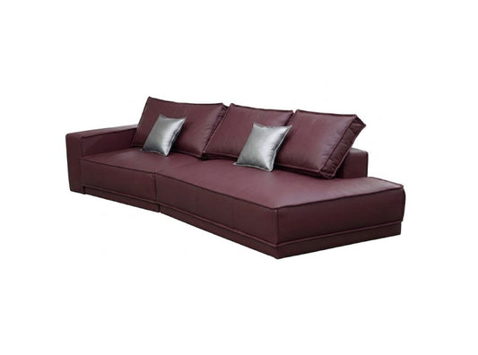 A modern low-profile sectional sofa upholstered in deep burgundy leather, featuring three matching back cushions and two shiny silver throw pillows, shown against a plain white background.