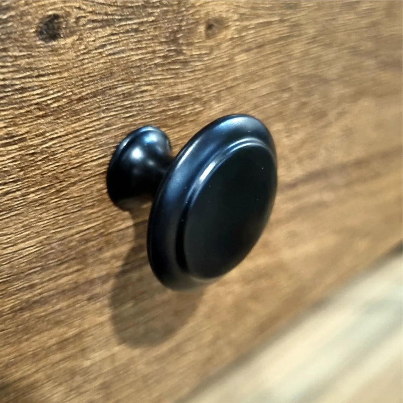 Black cabinet knob on a wooden surface