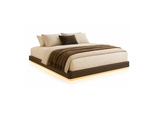 A modern low-profile platform bed with a dark brown frame and warm under-bed lighting, dressed in cream bedding and a brown throw blanket, set against a plain white background.