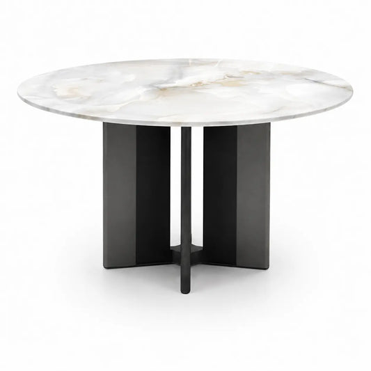 A round dining table with a white marble top featuring subtle gray and beige veining, supported by a matte black geometric pedestal base.
