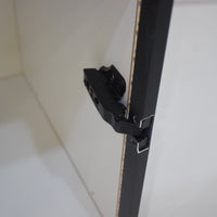 Close-up of a black cabinet handle on a white cabinet door.