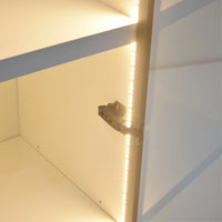 Close-up of a light fixture inside a cabinet with LED strip lighting.