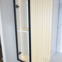 Long mirror with black frame leaning against a white wall.