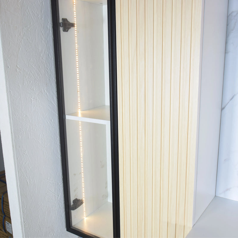 Long mirror with black frame leaning against a white wall.