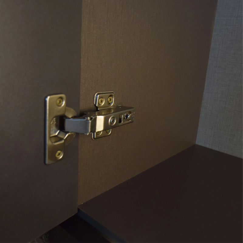Close-up of a gold cabinet hinge on a brown door