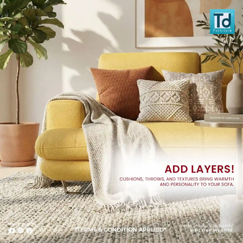 Yellow sofa with decorative pillows and a blanket in a living room setting, featuring TD Furniture logo.