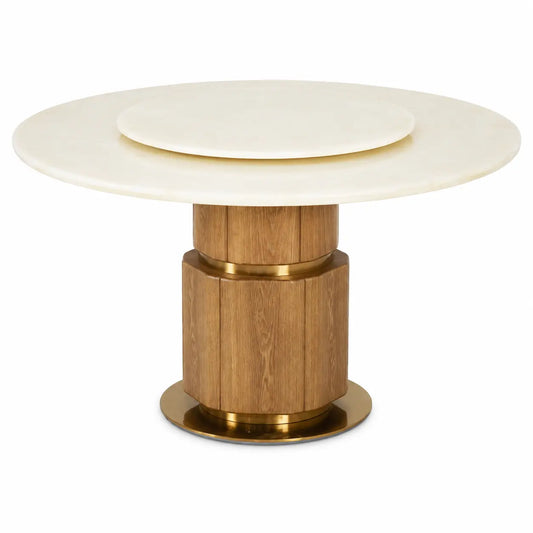 A round dining table featuring a cream-colored stone top with a concentric inner plate, supported by a fluted wooden pedestal base with polished brass accents.