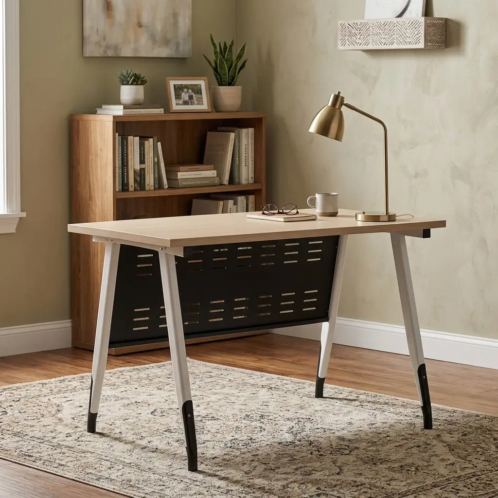 A modern writing desk with a light wood top, black metal storage basket underneath, and white legs with black tips, styled in a home office setting next to a brass desk lamp.