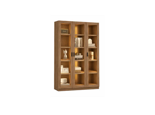A tall wooden bookcase with three glass-front doors and open shelves, shown against a plain white background. The bookcase is styled with books, decorative objects, and small plants.