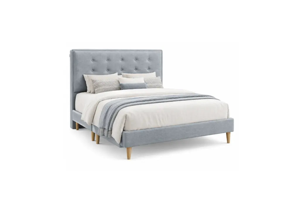A light gray upholstered bed frame with a tall button-tufted headboard and matching footboard, shown with white bedding, gray pillows, and a gray throw blanket on a plain white background.