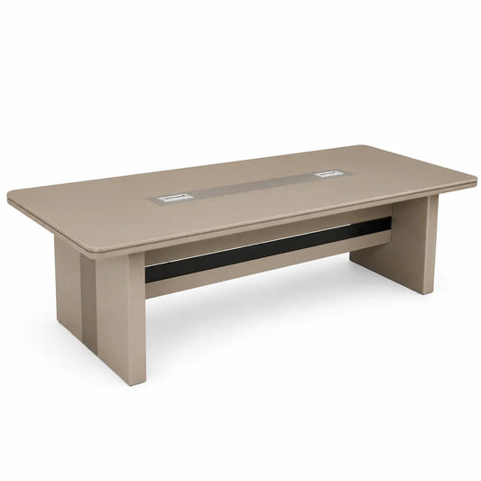 A modern rectangular conference table in a warm taupe-beige finish, featuring a central black cable management channel and two silver metal outlet covers on the tabletop, set against a plain white background.