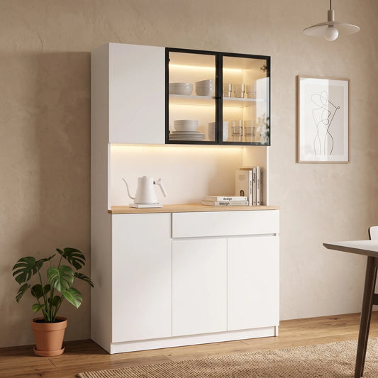 A modern white kitchen hutch with a light wood countertop, featuring a glass-front upper cabinet with black frames, warm LED lighting, and a white electric kettle on top, set against a beige textured wall in a styled room.