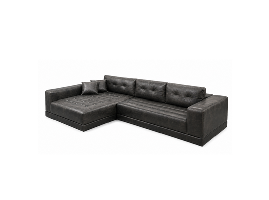 A dark gray tufted leather sectional sofa with a chaise lounge on the left side, shown from a three-quarter angle against a plain white background.