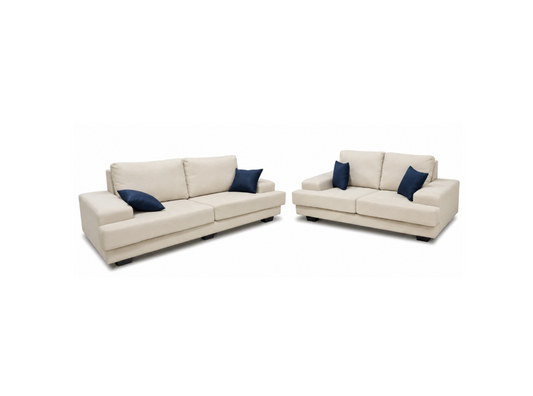 A modern beige sofa and matching loveseat set, each styled with two navy blue accent pillows, shown against a plain white background.