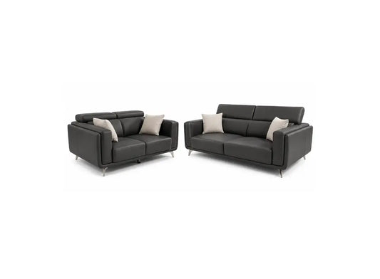 A modern two-piece sofa set consisting of a two-seater loveseat and a three-seater sofa, upholstered in dark charcoal gray leather with light beige accent pillows, shown on a plain white background.
