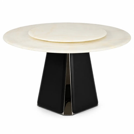 A modern round dining table featuring a cream-colored stone top with a concentric inner ring and a sculptural black faceted pedestal base.