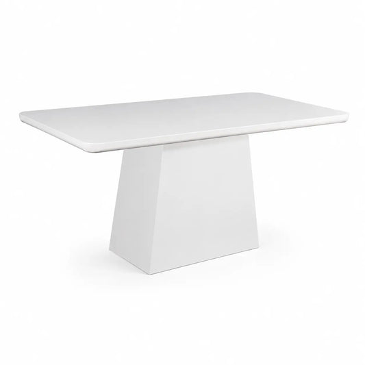 A modern white rectangular dining table with a thick, tapered geometric pedestal base, shown on a seamless white background.