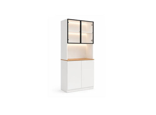 A modern white storage cabinet with a two-tier design, featuring a top glass-front display cabinet with black frames and warm interior lighting, a light wood countertop, and two lower white doors.