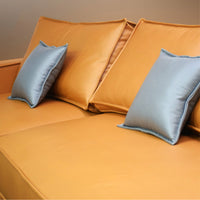 Orange sofa with blue pillows against a beige wall