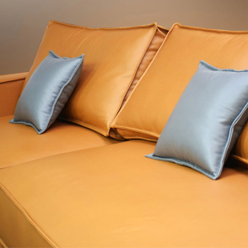 Orange sofa with blue pillows against a beige wall