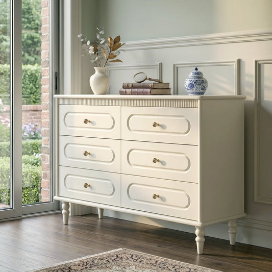 White dresser with decorative items in a room with large windows.