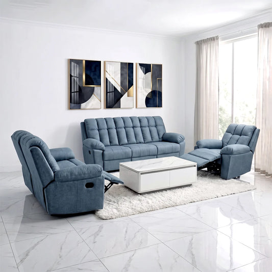 A staged living room featuring a blue tufted sofa, two matching blue recliners, a white coffee table, and a white shag rug. The room has white walls, marble-look tile floors, and a window with sheer curtains on the right, with abstract wall art above the sofa.