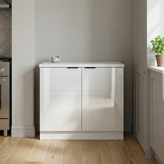 A modern white high-gloss two-door sideboard cabinet in a minimalist kitchen setting with light wood floors and neutral walls.