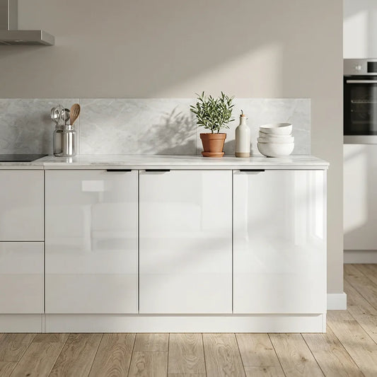 A modern kitchen cabinet unit in glossy white, shown in a real kitchen setting with a marble backsplash, wooden floor, and countertop decor including a potted plant and stacked bowls.