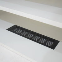Black floor vent on a white floor with a neutral wall background