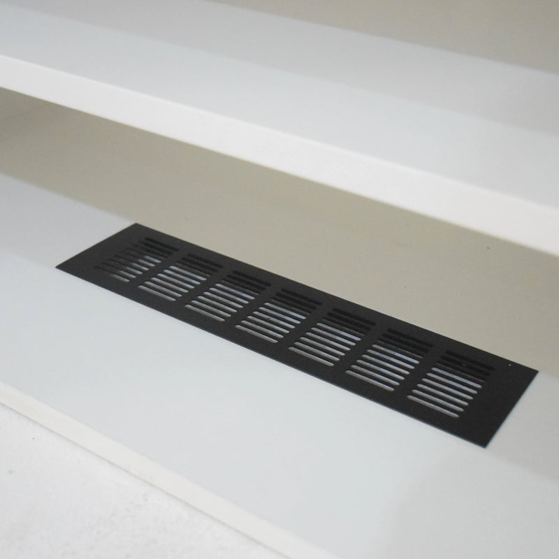 Black floor vent on a white floor with a neutral wall background