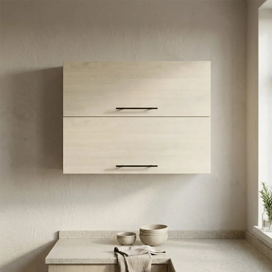 A modern wall-mounted double-drawer cabinet in a light natural wood finish with slim black horizontal bar handles, installed on a textured beige plaster wall above a matching stone countertop with ceramic bowls and a folded cloth.